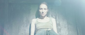 Movie still from “Department Q: The Keeper of Lost Causes” (2013), directed by Mikkel Nørgaard – A woman sitting on the ground in front of a cement wall; Close Up shot, Low angle