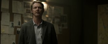 Movie still from “Department Q: The Keeper of Lost Causes” (2013), directed by Mikkel Nørgaard – A man wearing a suit and tie standing in a room; Close Up shot, Over the shoulder angle