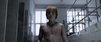 Movie still from “Department Q: The Keeper of Lost Causes” (2013), directed by Mikkel Nørgaard – A young boy is covered in blood in a room; Medium shot, Low angle