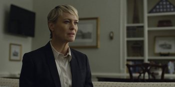 Movie still from “House of Cards” (2013), created by Beau Willimon – A woman with short blonde hair sitting in a room; Close Up shot, Over the shoulder angle