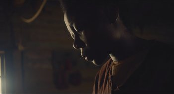 Movie still from “The Keeping Room” (2014), directed by Daniel Barber – A young man is looking down at the ground; Close Up shot, Low angle