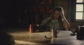 Movie still from “The Keeping Room” (2014), directed by Daniel Barber – A woman sitting at a table with a cup of coffee; Medium shot, High angle