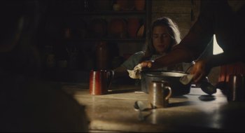Movie still from “The Keeping Room” (2014), directed by Daniel Barber – A woman is sitting at a table stirring a pot; Medium shot, High angle