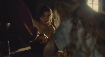 Movie still from “The Keeping Room” (2014), directed by Daniel Barber – A young girl sitting on the floor looking at something on the floor; Medium shot, High angle