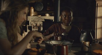 Movie still from “The Keeping Room” (2014), directed by Daniel Barber – Two people sitting at a table with a pot of food; Medium shot, Over the shoulder angle