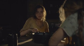 Movie still from “The Keeping Room” (2014), directed by Daniel Barber – A woman sitting at a table with a pan in front of her face; Medium shot, Over the shoulder angle