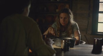 Movie still from “The Keeping Room” (2014), directed by Daniel Barber – A woman sitting at a table in front of a pot; Medium shot, Over the shoulder angle