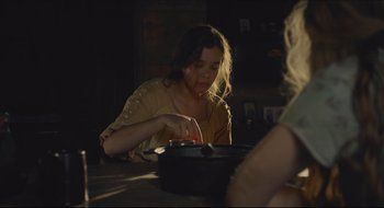 Movie still from “The Keeping Room” (2014), directed by Daniel Barber – A woman sitting at a table in front of a pot; Medium shot, High angle
