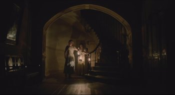 Movie still from “The Keeping Room” (2014), directed by Daniel Barber – Two women are walking down the stairs holding candles; Wide shot, Low angle