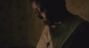 Movie still from “The Keeping Room” (2014), directed by Daniel Barber – A person with a cross on a necklace; Close Up shot, High angle