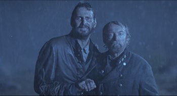 Movie still from “The Keeping Room” (2014), directed by Daniel Barber – Two men standing next to each other in the rain; Medium shot, Low angle