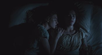 Movie still from “The Keeping Room” (2014), directed by Daniel Barber – Two people sleeping in a dark room with one of them holding her hand up to her chest; Close Up shot, Overhead angle