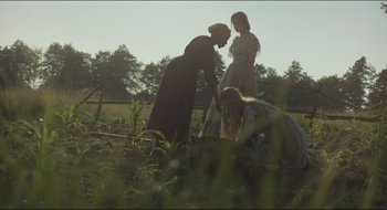 Movie still from “The Keeping Room” (2014), directed by Daniel Barber – Three women are tending to plants in a field; Medium shot, Low angle