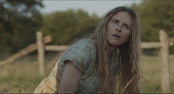 Movie still from “The Keeping Room” (2014), directed by Daniel Barber – A woman with long blonde hair is leaning against a fence; Close Up shot, Low angle