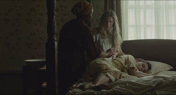 Movie still from “The Keeping Room” (2014), directed by Daniel Barber – A woman sitting on a bed next to another woman; Medium shot, High angle