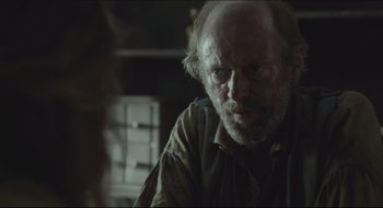 Movie still from “The Keeping Room” (2014), directed by Daniel Barber – An old man with a beard is sitting in a room; Close Up shot, Over the shoulder angle