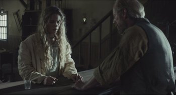 Movie still from “The Keeping Room” (2014), directed by Daniel Barber – A woman and a man sitting at a wooden table; Medium shot, Over the shoulder angle