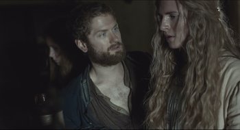 Movie still from “The Keeping Room” (2014), directed by Daniel Barber – A man and a woman standing next to each other in a dark room; Medium shot, Over the shoulder angle