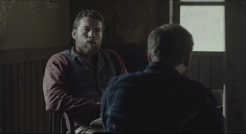 Movie still from “The Keeping Room” (2014), directed by Daniel Barber – A man sitting next to another man in a chair; Medium shot, Over the shoulder angle