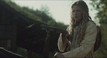 Movie still from “The Keeping Room” (2014), directed by Daniel Barber – A woman holding a gun while standing next to a tree; Medium shot, Low angle