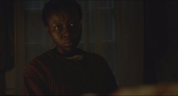 Movie still from “The Keeping Room” (2014), directed by Daniel Barber – A woman is looking at the camera in a dark room; Close Up shot, Over the shoulder angle