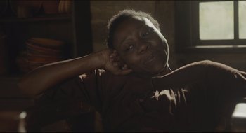Movie still from “The Keeping Room” (2014), directed by Daniel Barber – A woman sitting in a room with her hand behind her head; Close Up shot, High angle