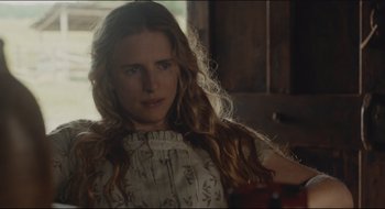 Movie still from “The Keeping Room” (2014), directed by Daniel Barber – A woman with long blonde curly hair wearing a white dress; Close Up shot, Over the shoulder angle