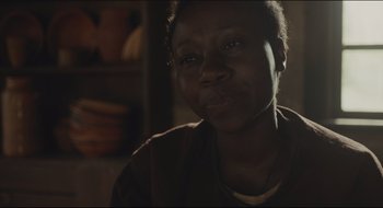 Movie still from “The Keeping Room” (2014), directed by Daniel Barber – An older african american woman sitting in front of a wooden table; Close Up shot, Over the shoulder angle