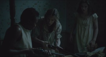 Movie still from “The Keeping Room” (2014), directed by Daniel Barber – A group of people standing around a table; Medium shot, Over the shoulder angle