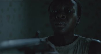 Movie still from “The Keeping Room” (2014), directed by Daniel Barber – A young man holding a gun in a dark room; Close Up shot, Over the shoulder angle