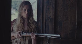 Movie still from “The Keeping Room” (2014), directed by Daniel Barber – A woman holding a gun in front of a wooden door; Medium shot, Low angle