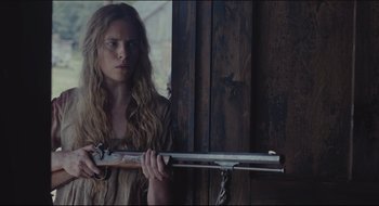 Movie still from “The Keeping Room” (2014), directed by Daniel Barber – A young woman holding a gun in a room; Medium shot, Low angle