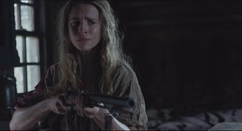 Movie still from “The Keeping Room” (2014), directed by Daniel Barber – A woman holding a rifle in a dark room; Close Up shot, Over the shoulder angle