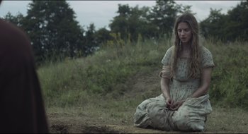 Movie still from “The Keeping Room” (2014), directed by Daniel Barber – A woman sitting on the ground in the grass; Medium shot, Low angle