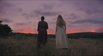 Movie still from “The Keeping Room” (2014), directed by Daniel Barber – Two women standing in a field looking at the sunset; Medium shot, Low angle