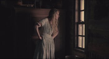 Movie still from “The Keeping Room” (2014), directed by Daniel Barber – A woman standing in front of a window in a room; Medium shot, Low angle