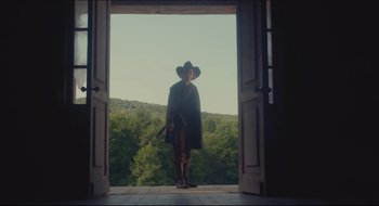 Movie still from “The Keeping Room” (2014), directed by Daniel Barber – A man standing in front of an open door with trees in the background; Wide shot, Low angle