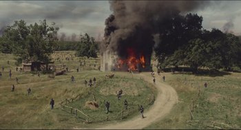 Movie still from “The Keeping Room” (2014), directed by Daniel Barber – A group of people in a field near a burning house; Extreme Wide shot, High angle