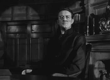 Movie still from “The Keys of the Kingdom” (1944), directed by John M. Stahl – An older man sitting at a table in a room; Medium shot, Low angle