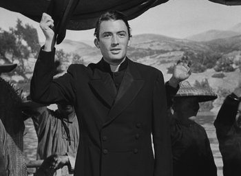 Movie still from “The Keys of the Kingdom” (1944), directed by John M. Stahl – A black and white photo of a man holding an umbrella; Medium shot, Low angle