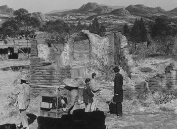 Movie still from “The Keys of the Kingdom” (1944), directed by John M. Stahl – A group of people standing around a stone wall; Extreme Wide shot, Over the shoulder angle