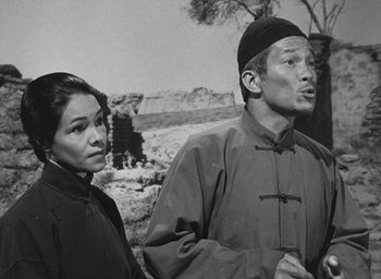 Movie still from “The Keys of the Kingdom” (1944), directed by John M. Stahl – A man and a woman standing next to each other in front of trees; Medium shot, Low angle