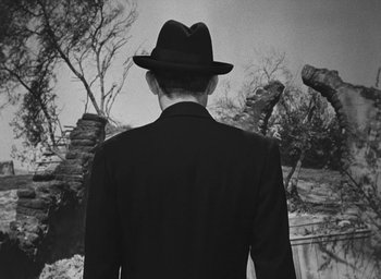 Movie still from “The Keys of the Kingdom” (1944), directed by John M. Stahl – A man in a suit and a hat is looking at a tree; Close Up shot, Low angle