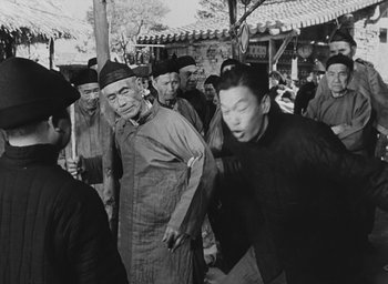 Movie still from “The Keys of the Kingdom” (1944), directed by John M. Stahl – A group of men standing around each other in front of a building; Medium shot, Over the shoulder angle