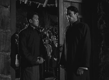 Movie still from “The Keys of the Kingdom” (1944), directed by John M. Stahl – Two men standing next to each other in front of a crowd of onlookers; Medium shot, Low angle