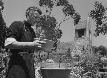 Movie still from “The Keys of the Kingdom” (1944), directed by John M. Stahl – An old photo of a man holding a plate near a grill; Medium shot, Low angle