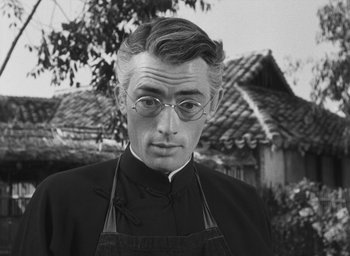 Movie still from “The Keys of the Kingdom” (1944), directed by John M. Stahl – A man wearing a priest's outfit and glasses in front of a house; Close Up shot, Low angle
