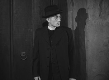 Movie still from “The Keys of the Kingdom” (1944), directed by John M. Stahl – A man in a suit and hat standing in front of a door; Medium shot, Low angle