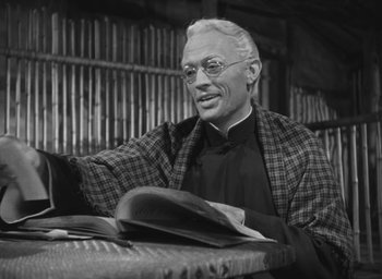 Movie still from “The Keys of the Kingdom” (1944), directed by John M. Stahl – An older man sitting at a table with a book in front of him; Medium shot, Low angle