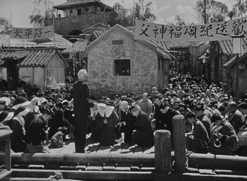 Movie still from “The Keys of the Kingdom” (1944), directed by John M. Stahl – An old photo of a crowd of people sitting on a platform; Wide shot, High angle